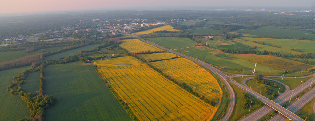 Aerial view of highway through farmers fields with small town in distance